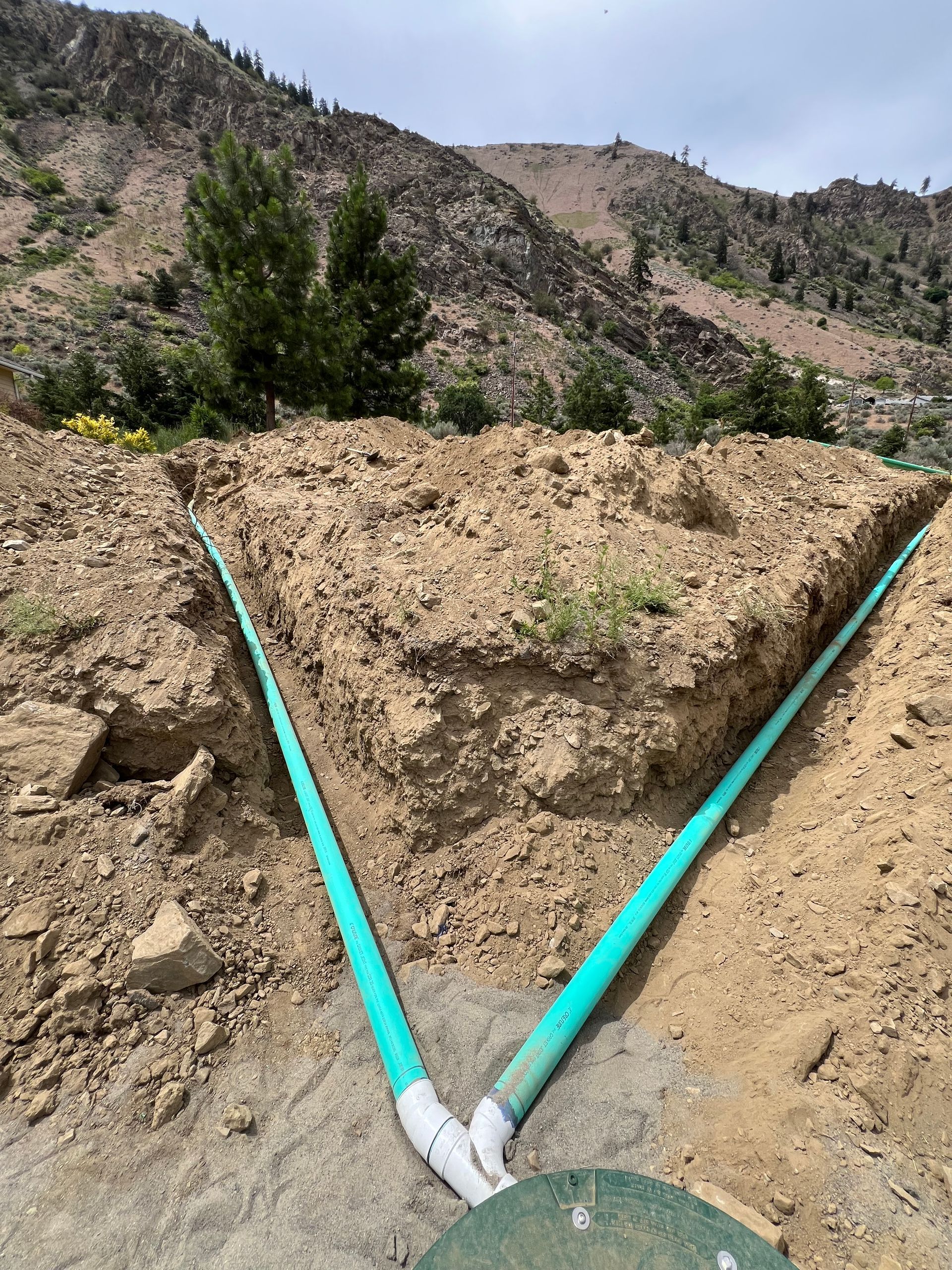 Two green pipes are connected to each other in the dirt.